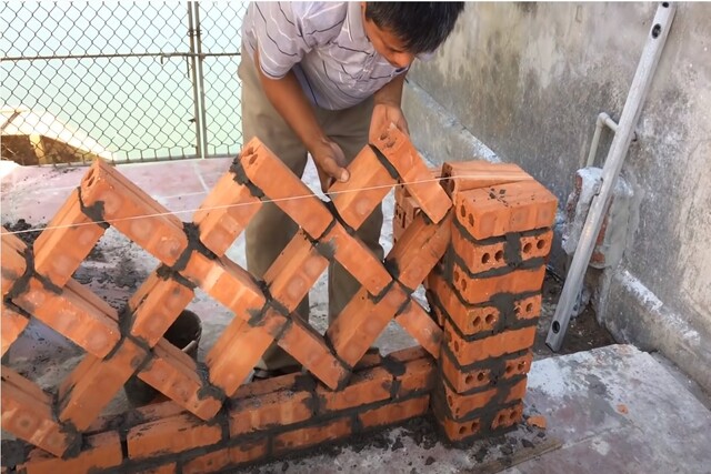 Unique brick wall being built by worker